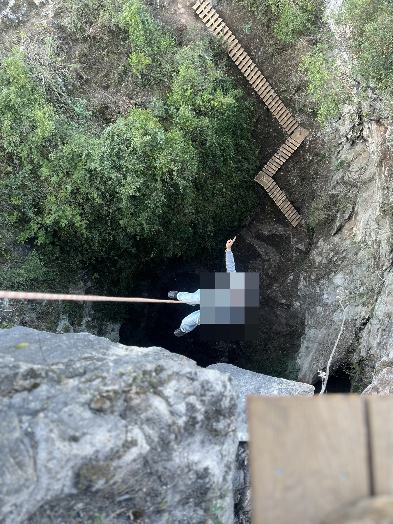 A harnessed participant on a rope above a rock opening