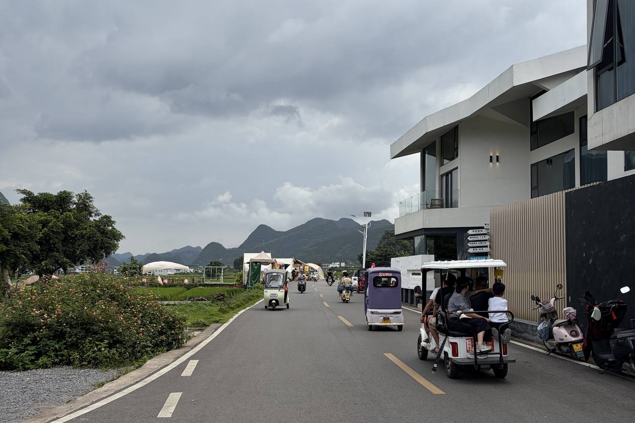 Electric buggies, bikes and cars sharing an open road through the Wanfenglin valley, karst peaks behind